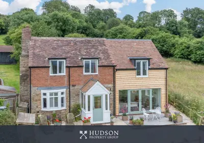 a brick house with white windows and doors at Modern Snitton Cottage & Gardens in Ludlow