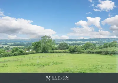a large green field with a fence in the distance at Modern Snitton Cottage & Gardens in Ludlow