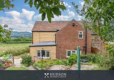 a brick house in a field with a garden at Modern Snitton Cottage & Gardens in Ludlow