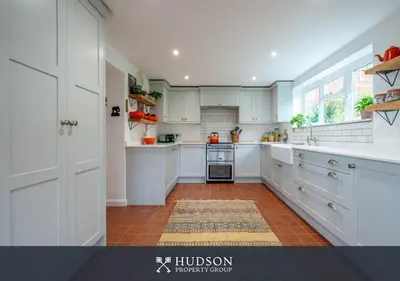 a kitchen with white cabinets and a red tile floor at Modern Snitton Cottage & Gardens in Ludlow