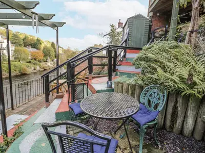 a patio with a table and chairs next to a fence at Bryn Dwr in Llangollen