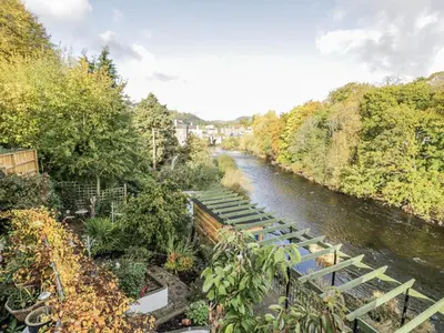 a river with a bunch of benches next to a bridge at Bryn Dwr in Llangollen