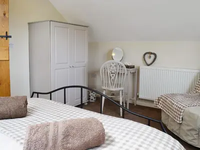 a bedroom with two beds and a table and a chair at Caeley Barn in Penybont