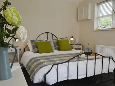 a bedroom with a bed with green pillows at Caeley Barn in Penybont