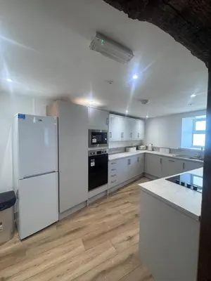 a large white kitchen with white appliances and wooden floors at 4 Bedroom All En suite Central Townhouse Ideal for Groups in Builth Wells