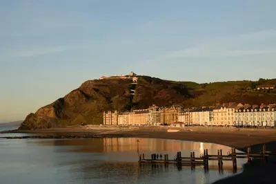 a group of buildings on a hill next to the water at The Granary Aberystwyth in Aberystwyth