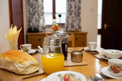 a table with a glass of orange juice and a loaf of bread at The Granary Aberystwyth in Aberystwyth