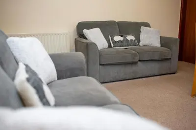a couch and a chair in a living room with pillows at The Granary Aberystwyth in Aberystwyth