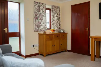 a living room with a wooden cabinet and a window at The Stable Aberystwyth in Aberystwyth