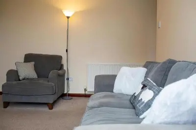 a living room with a couch and a chair and a lamp at The Stable Aberystwyth in Aberystwyth