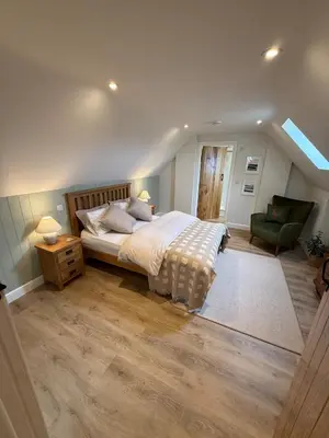 a bedroom with a bed and a green chair at Minafon Loft in Meifod