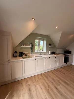 an attic kitchen with white cabinets and a sink at Minafon Loft in Meifod