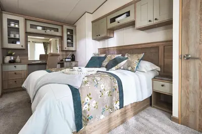 a bedroom with a large bed and a kitchen at Lodge - Sleeps 4 Near beach & Free parking in Llanina