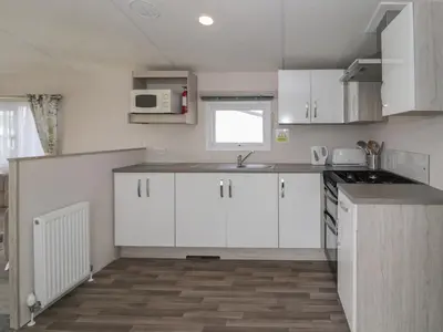 a small kitchen with white cabinets and a sink at Gold Caravan 316 in Talybont