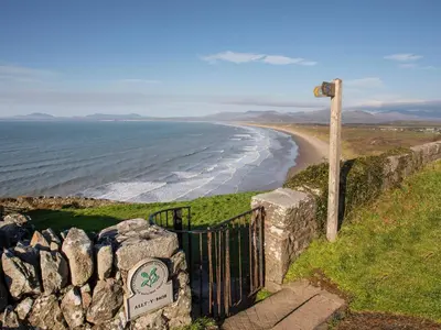 a gate on a hill next to a beach at Gold Caravan 316 in Talybont