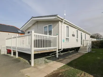 a white house with a porch and a white railing at Gold Lodge 201 in Talybont