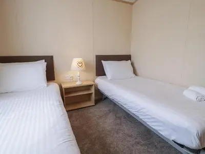 a room with two beds and a night stand with a lamp at Gold Lodge 201 in Talybont