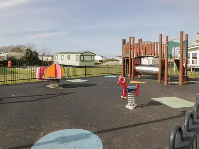 a playground with two play equipment in a park at Gold Caravan 203 in Talybont