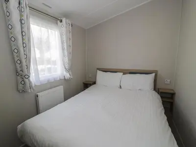 a bedroom with a white bed and a window at Gold Caravan 203 in Talybont