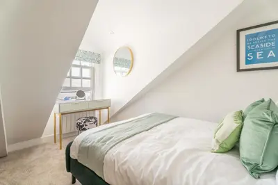 a white bedroom with a bed and a desk at Mermaid's Apartment by Ty Annie Holidays in New Quay