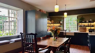 a dining room with a table and chairs and a kitchen at Tyddyn Eglwys in Talsarnau