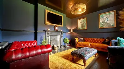 a living room with red leather furniture and a fireplace at Tyddyn Eglwys in Talsarnau