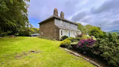 an old brick house with a grass yard at Tyddyn Eglwys in Talsarnau