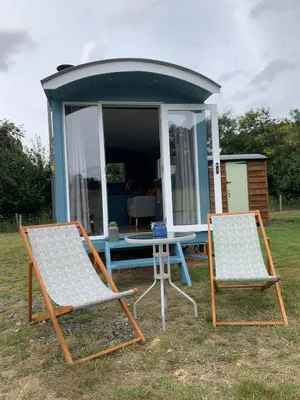 two chairs and a table in front of a house at Tower Farm Holidays - Shepherd's Huts in Llangollen