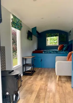 a living room with a couch and a bed at Tower Farm Holidays - Shepherd's Huts in Llangollen