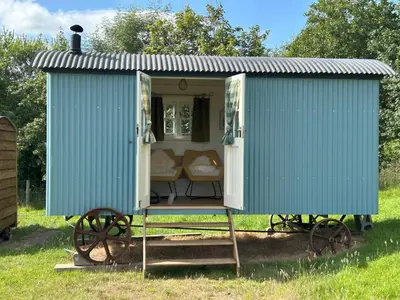 a blue train house with a couch in it at Tower Farm Holidays - Shepherd's Huts in Llangollen