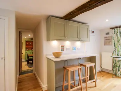 a kitchen with green cabinets and two stools at 41 High Street in Bishops Castle