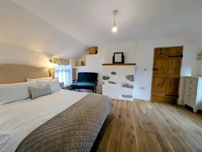 a bedroom with a large bed and a blue chair at Ty Isaf Welsh Farmhouse with Sea Views in Llanddwywe