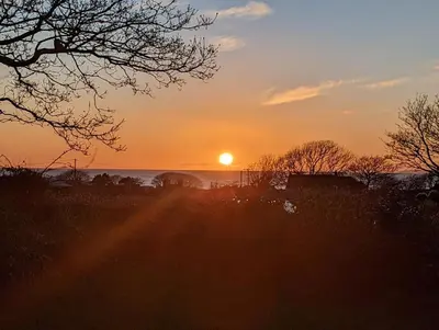 a sunset in a field with the sun in the sky at Ty Isaf Welsh Farmhouse with Sea Views in Llanddwywe