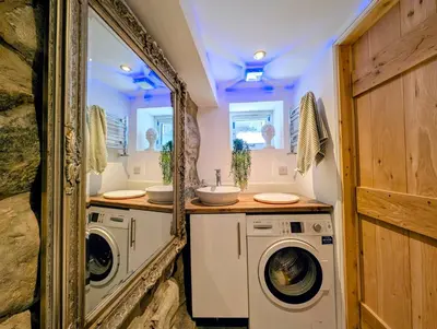 a bathroom with two washing machines and a sink at Ty Isaf Welsh Farmhouse with Sea Views in Llanddwywe