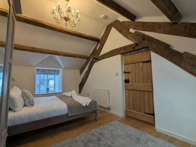 a bedroom with a bed and a chandelier at Ty Isaf Welsh Farmhouse with Sea Views in Llanddwywe