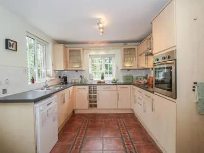 a kitchen with white cabinets and a tile floor at 2 Aqueduct Cottages in Wrexham
