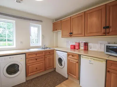a kitchen with wooden cabinets and a washer and dryer at 2 Aqueduct Cottages in Wrexham