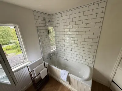a white bathroom with a tub and a window at 2 Aqueduct Cottages in Wrexham