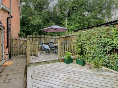 a wooden deck with a table and an umbrella at 2 Aqueduct Cottages in Wrexham