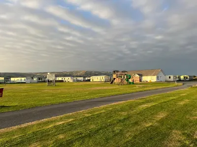 a road next to a field with a playground at Beach Retreat in Ynys-lâs Station