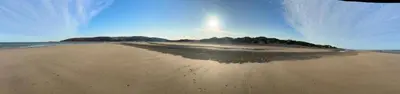 a view of a sandy beach with trees in the distance at Beach Retreat in Ynys-lâs Station