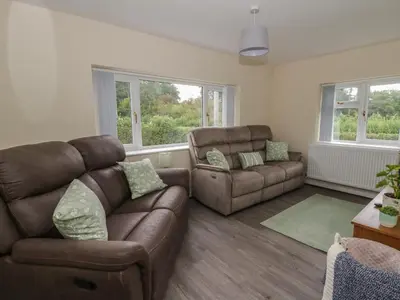 a living room with a leather couch and a chair at Glandwr House in Llandrindod Wells