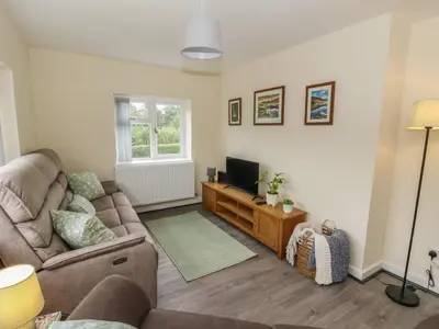 a living room with a couch and a television at Glandwr House in Llandrindod Wells