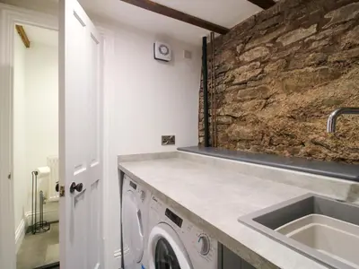 a laundry room with a sink and a stone wall at Raven Lane Retreat in Ludlow