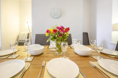 a table with white plates and a vase of flowers at 4 Bed in Barmouth oc-n32921 in Barmouth