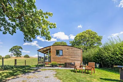 a small cabin in a field with a table and benches at 1 Bed in Llandeilo oc-w33068 in Llanddeusant