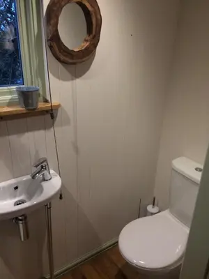 a bathroom with a toilet and a sink and a mirror at The Farm Hut in Barmouth