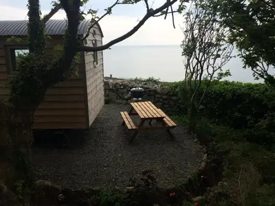 a picnic table next to a building with a grill at The Farm Hut in Barmouth