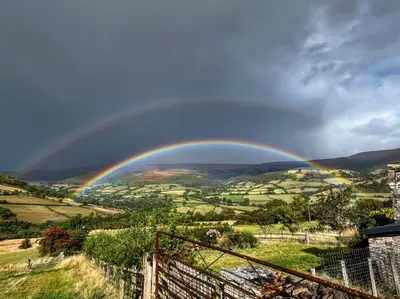 a rainbow in the sky over a field at Mountain View Farm Cottage in Crickhowell