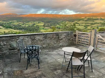 two chairs and a table on a patio with a view at Mountain View Farm Cottage in Crickhowell